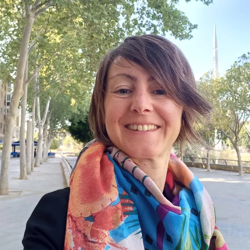 Mujer sonriendo con una ruta al fondo con árboles